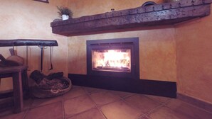 A fireplace with a tiled floor and a wooden shelf above it.