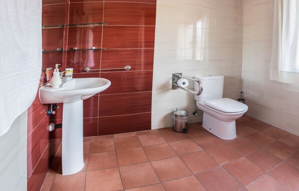 A bathroom with a white sink, a toilet, and a shower area.