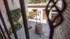 A courtyard with a stone floor, a wooden cart, and a water pump.