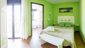 A bedroom with a bed, a bedside table, a bench, a green wall, and a painting.