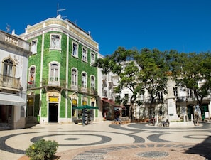 Edificio histórico con fachada verde, un patio central de pavimento estampado y una estatua.