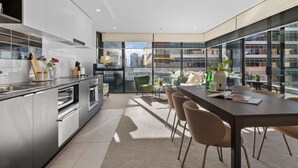 A modern kitchen with a dining area, large windows, and a view of the cityscape.