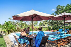 A poolside area with lounge chairs, umbrellas, and a pool. - The Dukuh Retreat (Tabanan)