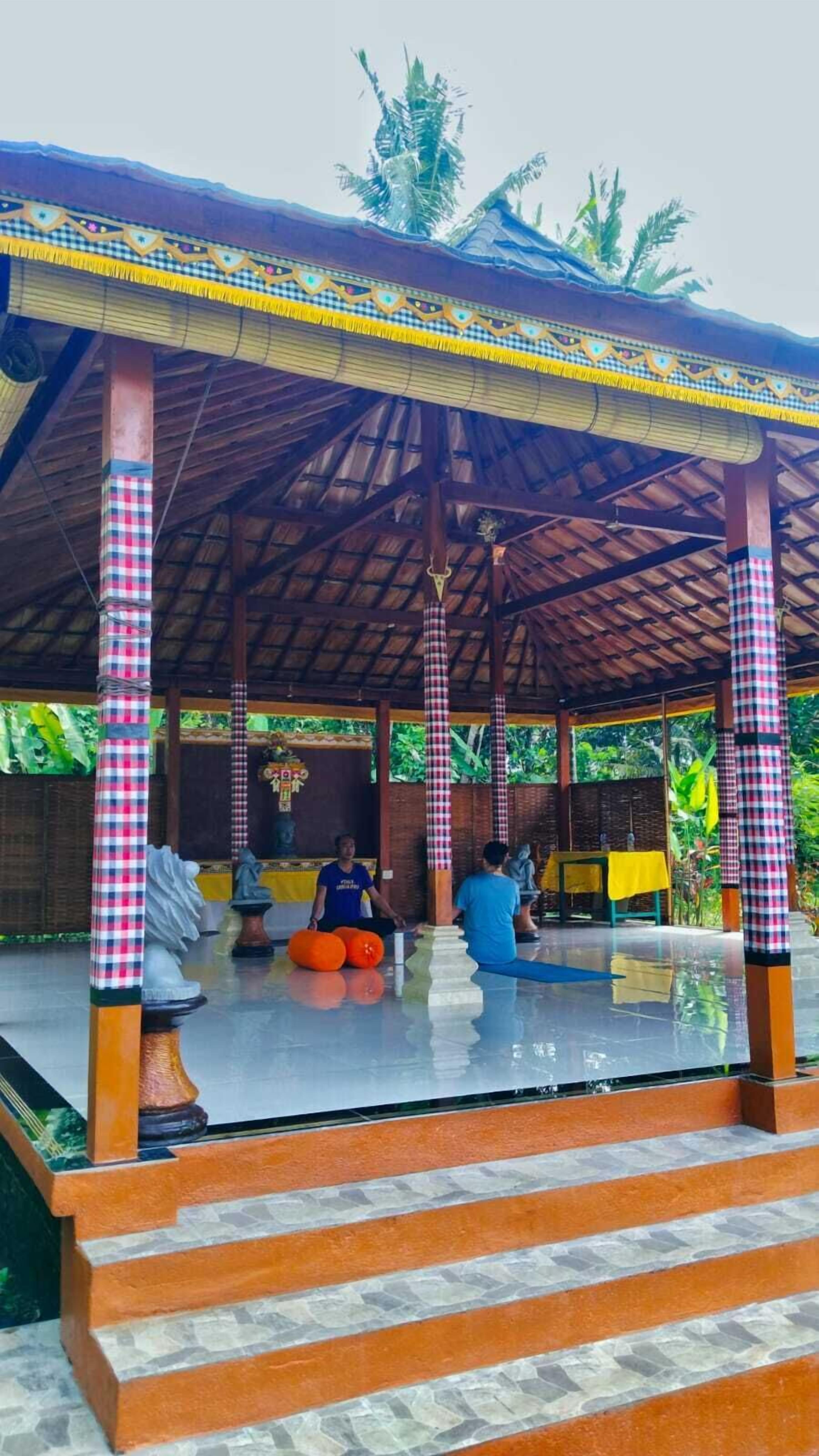 A covered outdoor area with checkered pillars, a tiled floor, and steps leading up to a seating area.