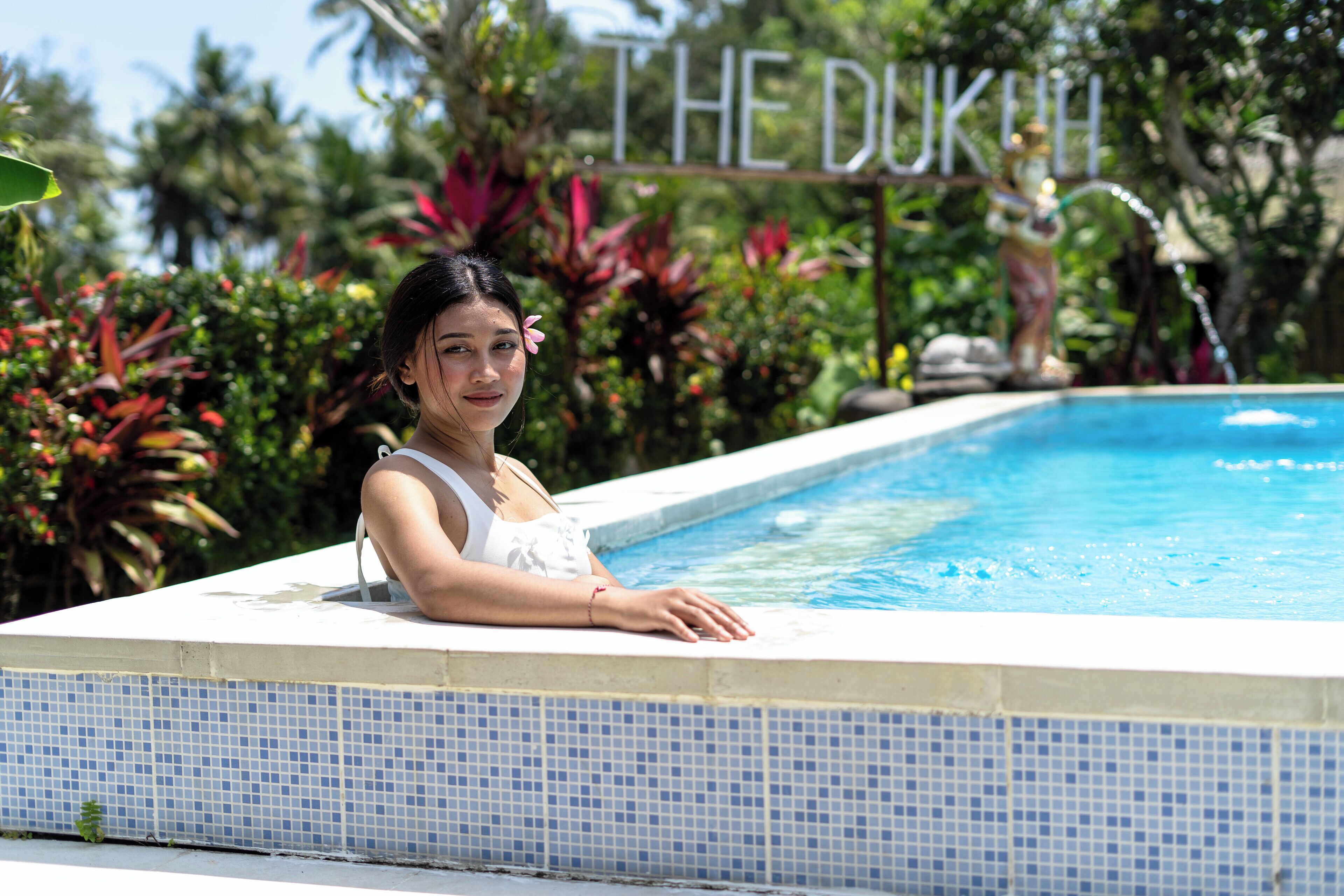 Una piscina al aire libre, sombrillas, sillones reclinables de piscina