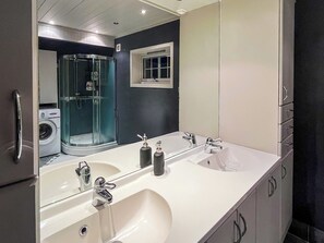 A modern bathroom with a double sink, a large mirror, and a glass shower enclosure. - JX Homestay (Ringerike)