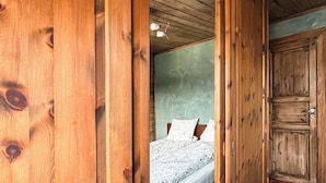 A wooden room with a bed, a wardrobe, and a door leading to another room. - JX Homestay (Ringerike)