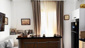 A compact kitchen with a bar area, a refrigerator, and a clock on the wall. - 3-bedroom bed & breakfast in enjoyable Cairo Governorate with AC (Cairo Governorate)