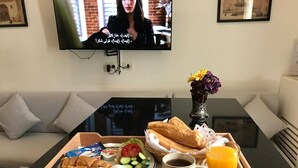 A breakfast tray with croissants, eggs, tomatoes, cucumbers, bread, and juice on a table in a hotel room. - 3-bedroom bed & breakfast in enjoyable Cairo Governorate with AC (Cairo Governorate)