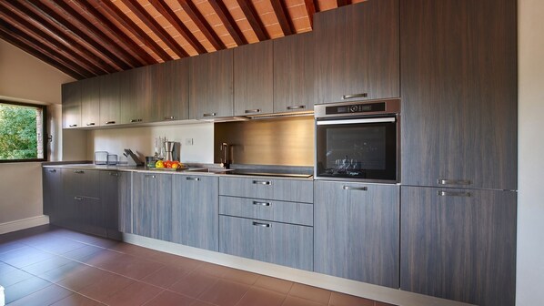 A modern kitchen with grey cabinetry, a built-in oven, and a window providing natural light.