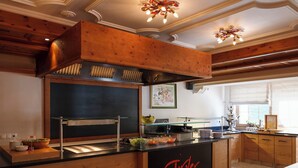 A kitchen with wooden cabinets, a black countertop, and a sign reading 'Tirler Hot.' - Gästehaus Wildschütz (Tux)