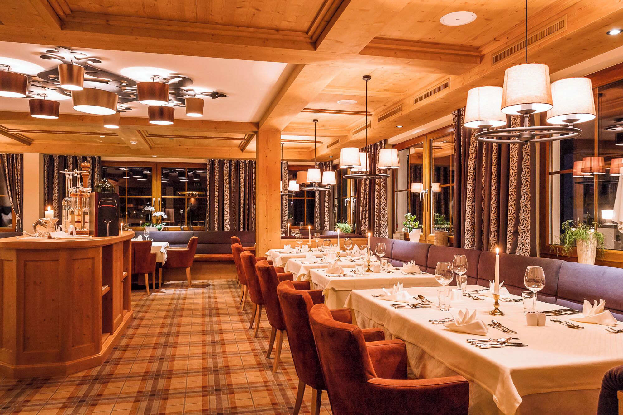 A restaurant with a long dining table, multiple chairs, and a bar area.