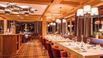 A restaurant with a long dining table, multiple chairs, and a bar area.