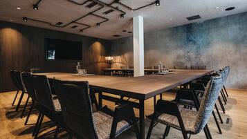A conference room with a long table, chairs, and a television screen.