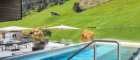 A swimming pool with a view of a green hillside and a building in the background.