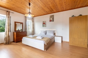 A bedroom with a wooden ceiling, a bed with white bedding, a wooden dresser, a wardrobe, and a window with curtains. - Country House 'Serenity' with Private Terrace, Wi-Fi, and Air Conditioning (Paxoi)