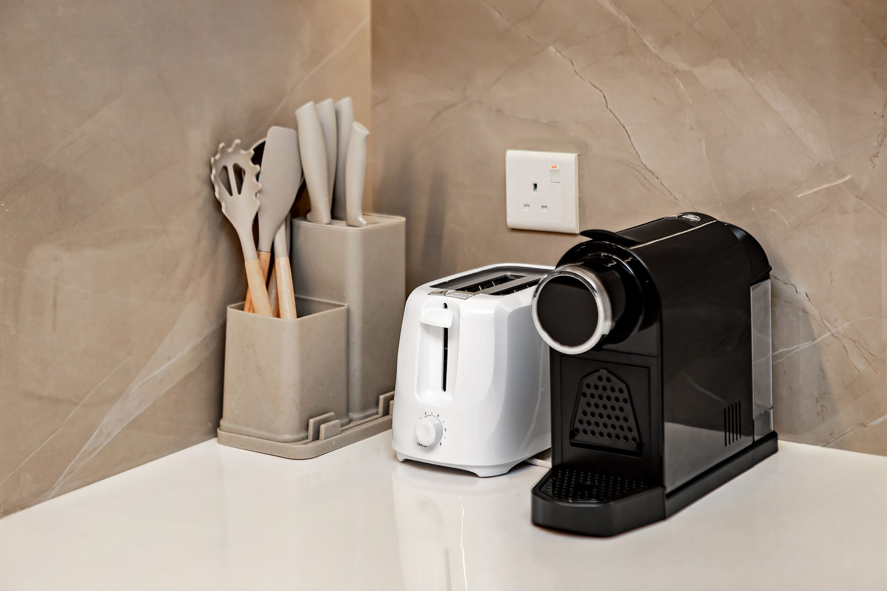 Eine Küchenarbeitsplatte mit Kaffeemaschine, Toaster und Besteckhalter.