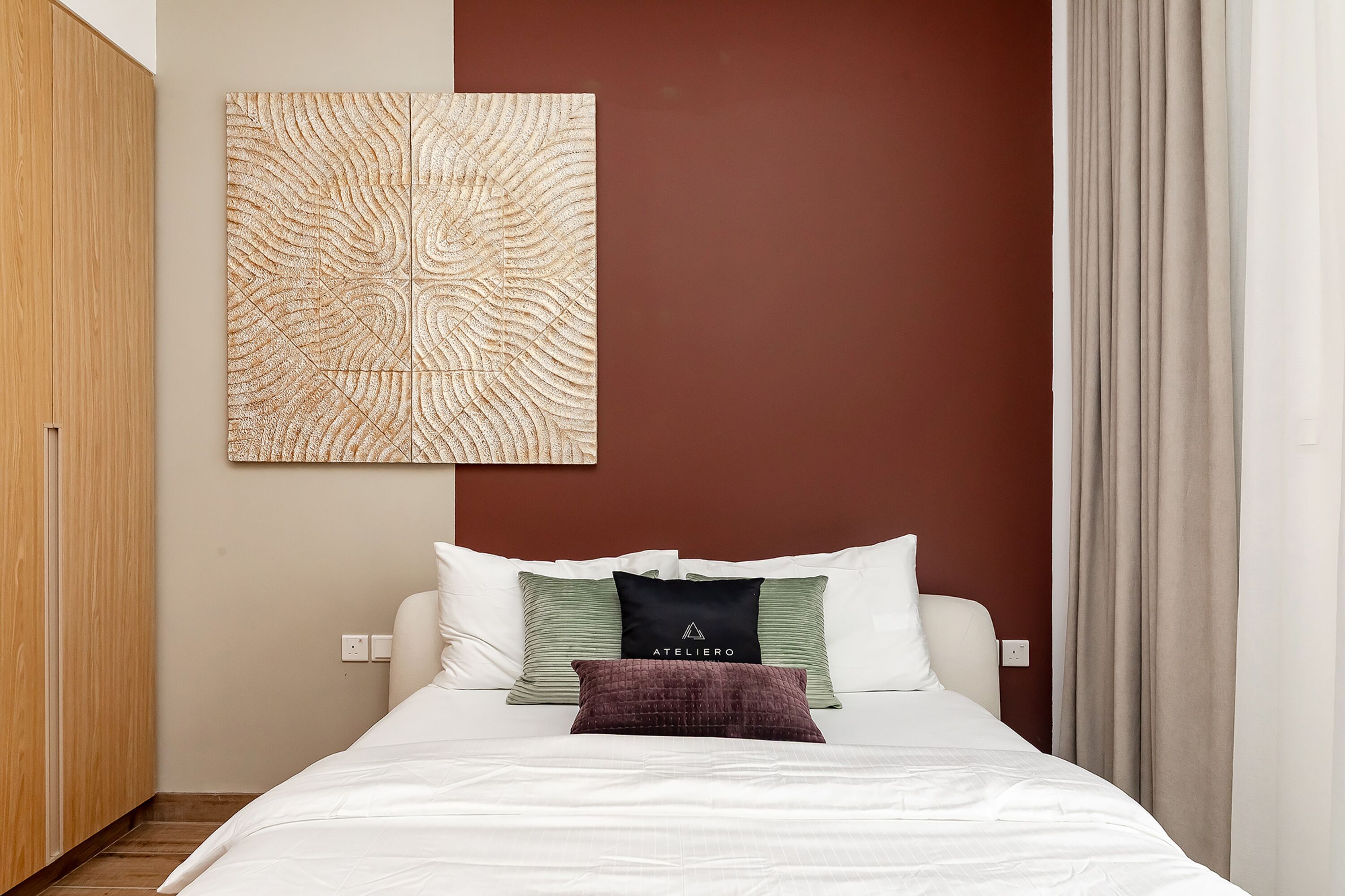 Ein ordentlich bezogenes Bett mit weißer Bettwäsche, eine braune Wand und ein großes abstraktes Kunstwerk darüber.