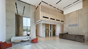 Un hall d’entrée spacieux avec un comptoir d’accueil, un canapé blanc et un fauteuil rouge.