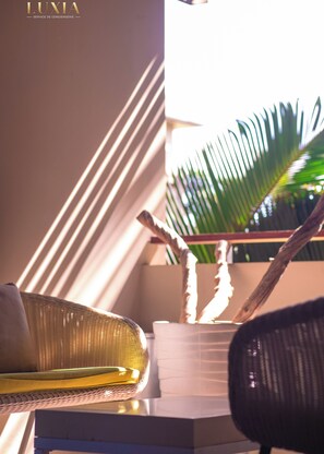 A wicker chair with a yellow cushion, a black office chair, and a white planter with a plant. - Luxury apartment at Domaine des Alizées Club & Spa, Grand Baie (Grand Baie)