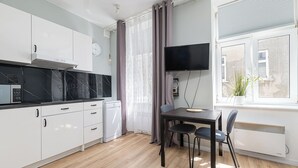 Uma cozinha moderna com armários brancos, um micro-ondas preto e um espaço de refeições com mesa e cadeiras.