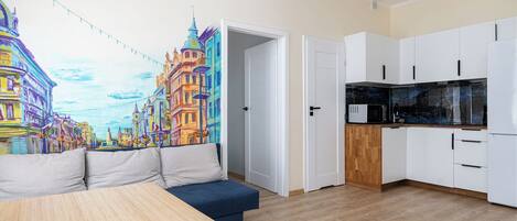 Un apartamento moderno con un mural vibrante de la ciudad, un espacio de descanso acogedor y una cocina compacta.