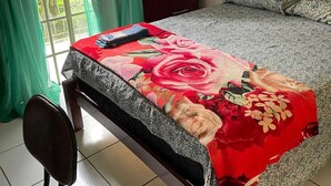 A bedroom with a bed, a desk, and a chair. There is a window with curtains, a wardrobe, and a wall-mounted air conditioning unit. - Aldeia da Mata - near the sea (Arraial d'Ajuda)