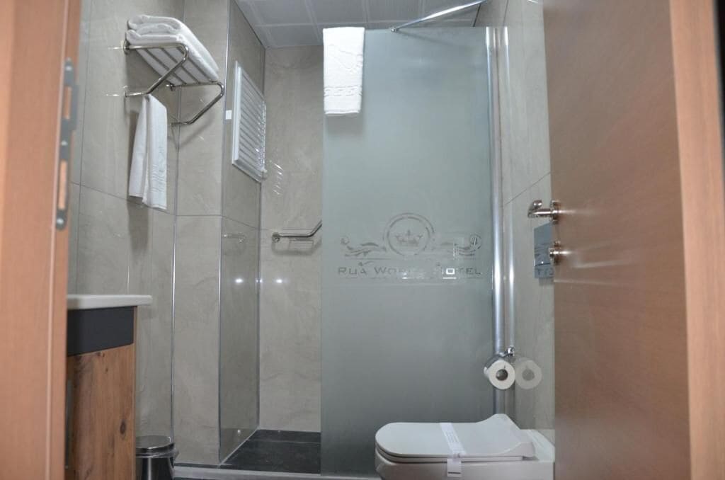 Un’area doccia vetrata con un water e un portasciugamani.