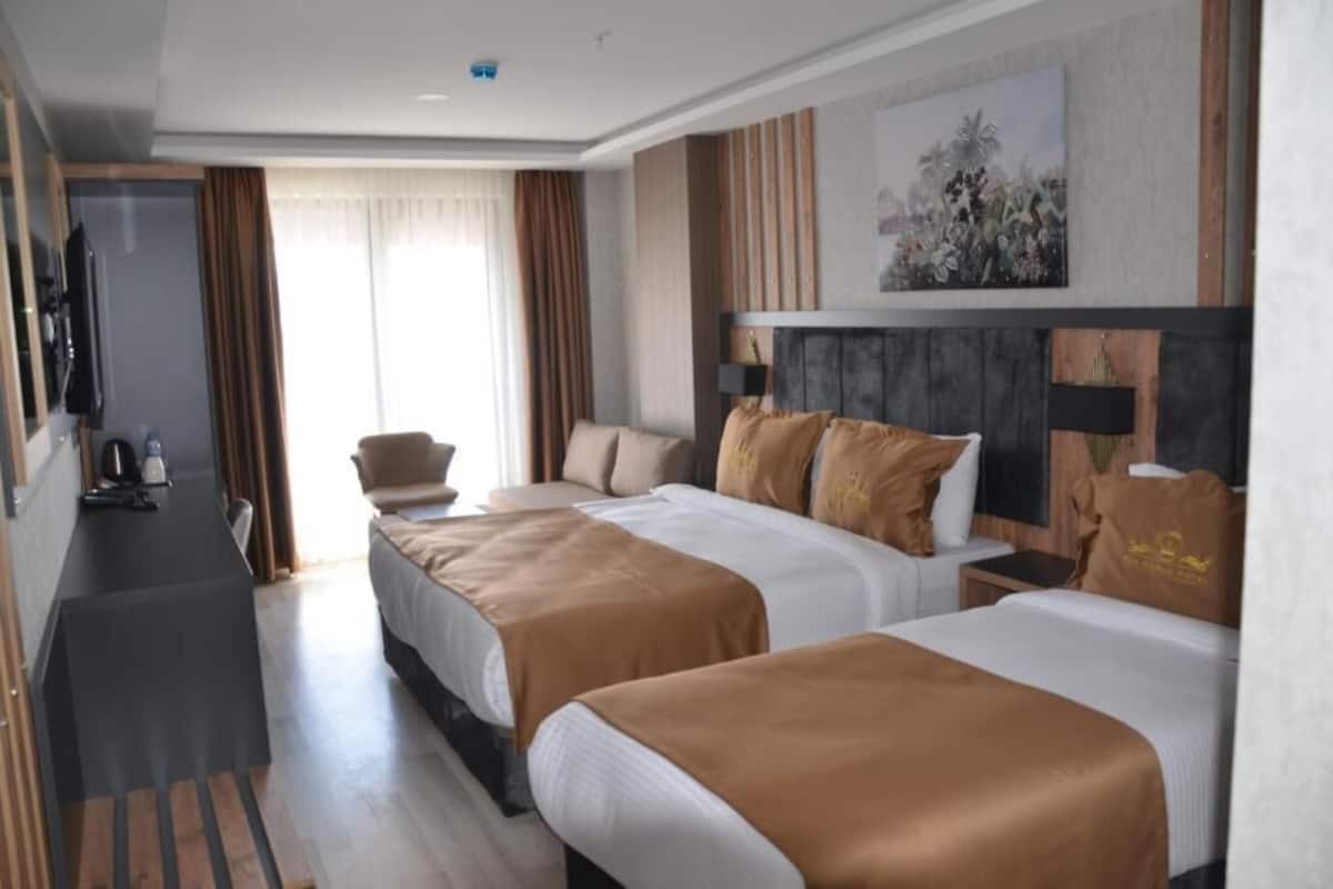 Ein Hotelzimmer mit zwei Betten, einem Schreibtisch, einem Sessel und einem Bild an der Wand.