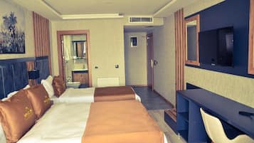 Een hotelkamer met twee bedden, een bureau, een televisie en een badkamer.