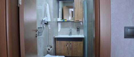 Un baño pequeño con inodoro, lavamanos y espejo.