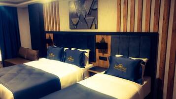 A hotel room with two beds, each with matching headboards and pillows, and a wooden panel wall.