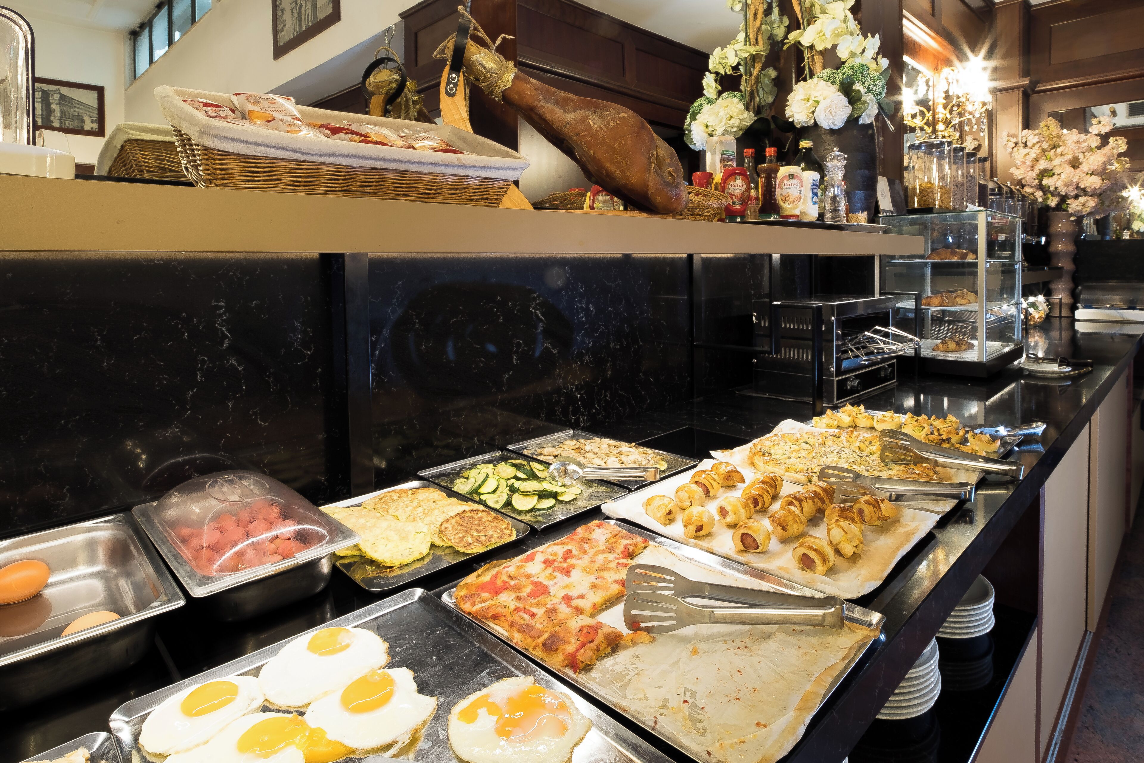 A buffet with various food items including eggs, meats, and pastries.