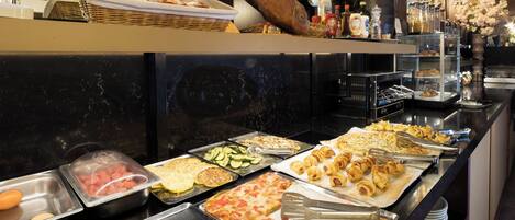 A buffet with various food items including eggs, meats, and pastries.
