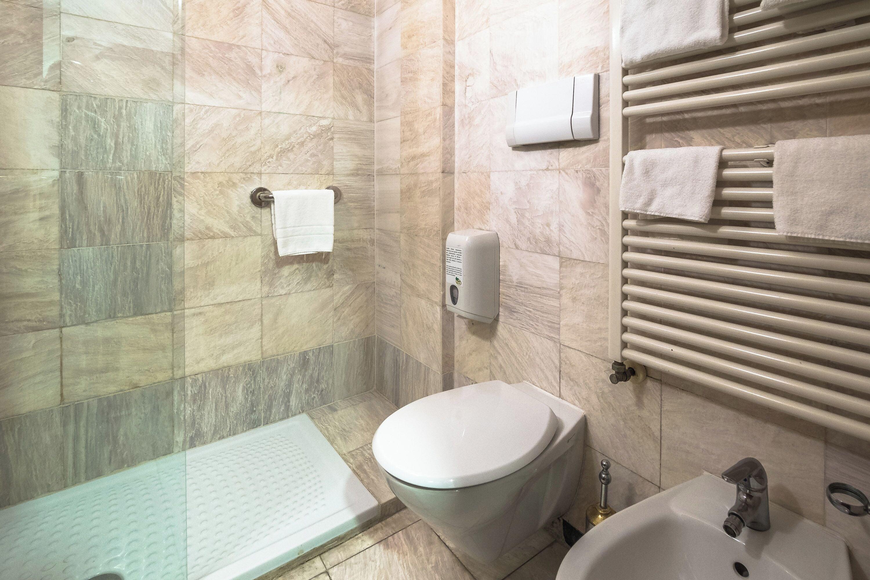 Une salle de bain avec une douche à parois de verre, des toilettes, un lavabo et un porte-serviettes avec des serviettes.