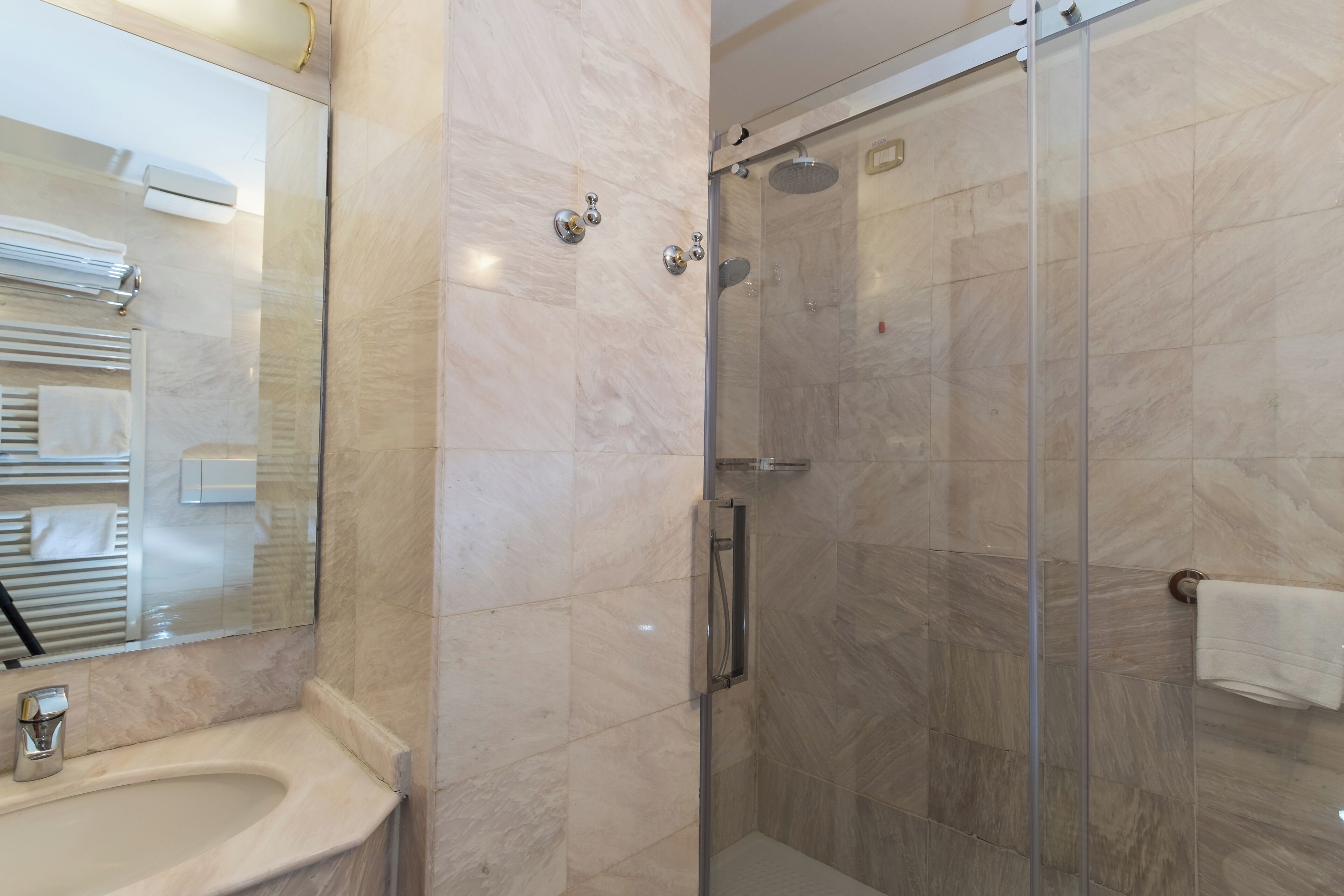 Een moderne badkamer met een glazen douchecabine, een wastafel en een spiegel.