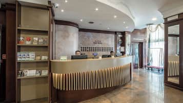 Un comptoir d’accueil d’hôtel avec une horloge et un panneau indiquant l’emplacement de la consigne à bagages.