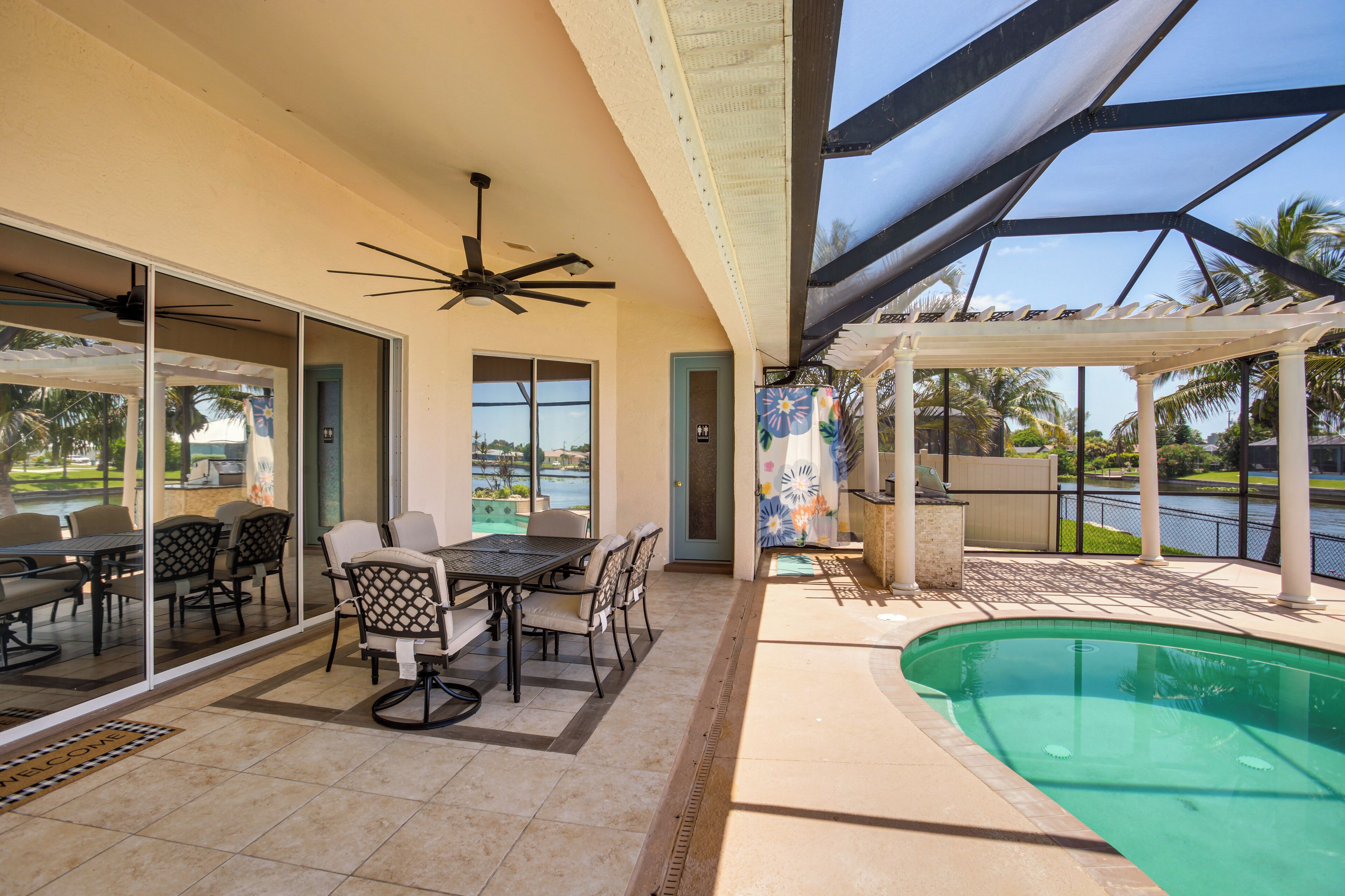 An outdoor patio with a pool, a covered seating area, and a dining table with chairs.