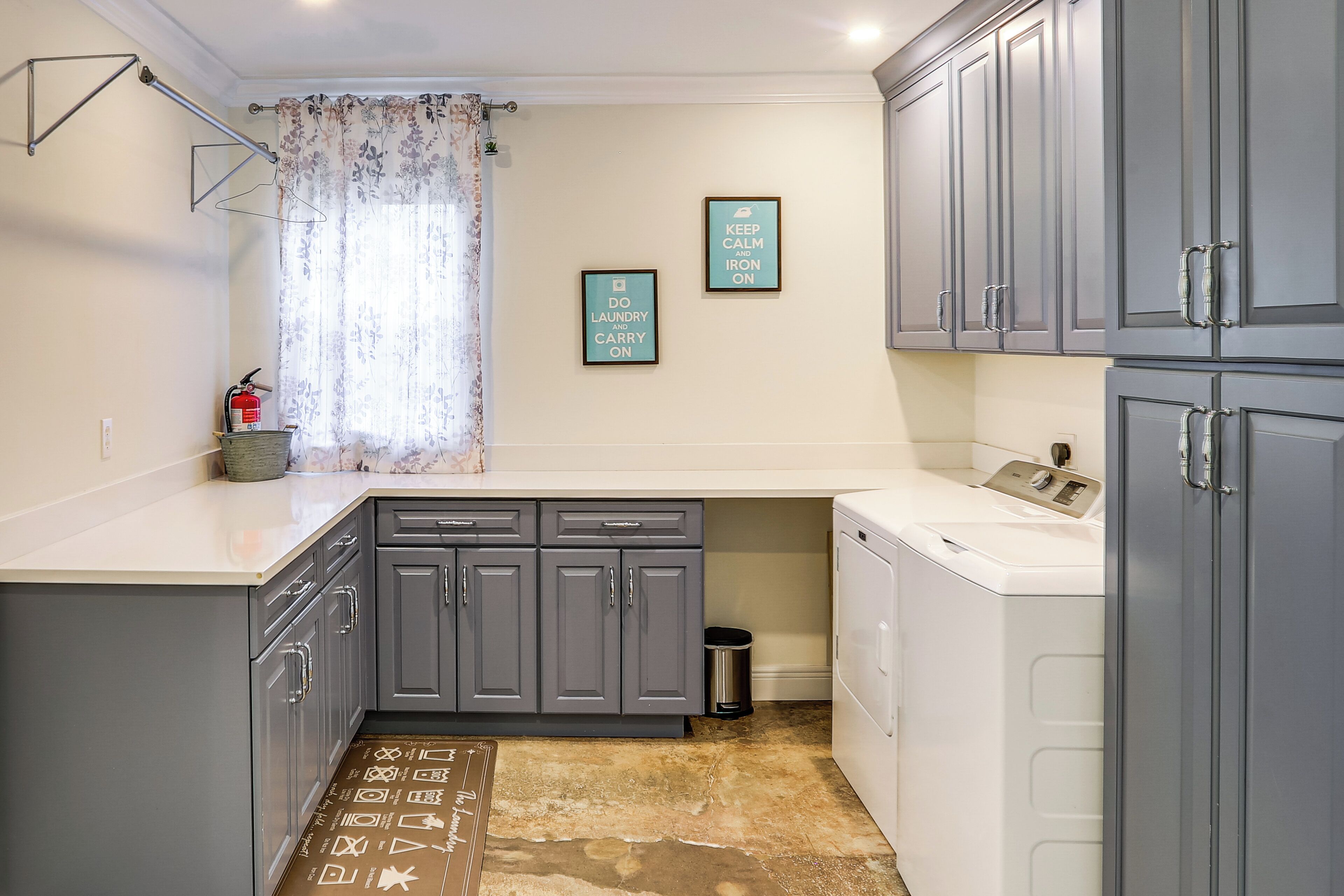 A laundry room with grey cabinets, a washing machine, and a drying rack.