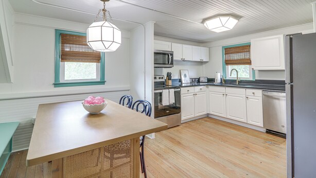 A kitchen with white cabinets, a wooden table, and a bowl of fruit. - Walk to Bars, Bites + Bands: Bold Athens Getaway! (Athens)
