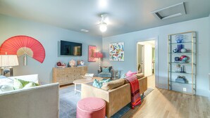 A living room with a sofa, a coffee table, a red fan, and a bookshelf. - Walk to Bars, Bites + Bands: Bold Athens Getaway! (Athens)