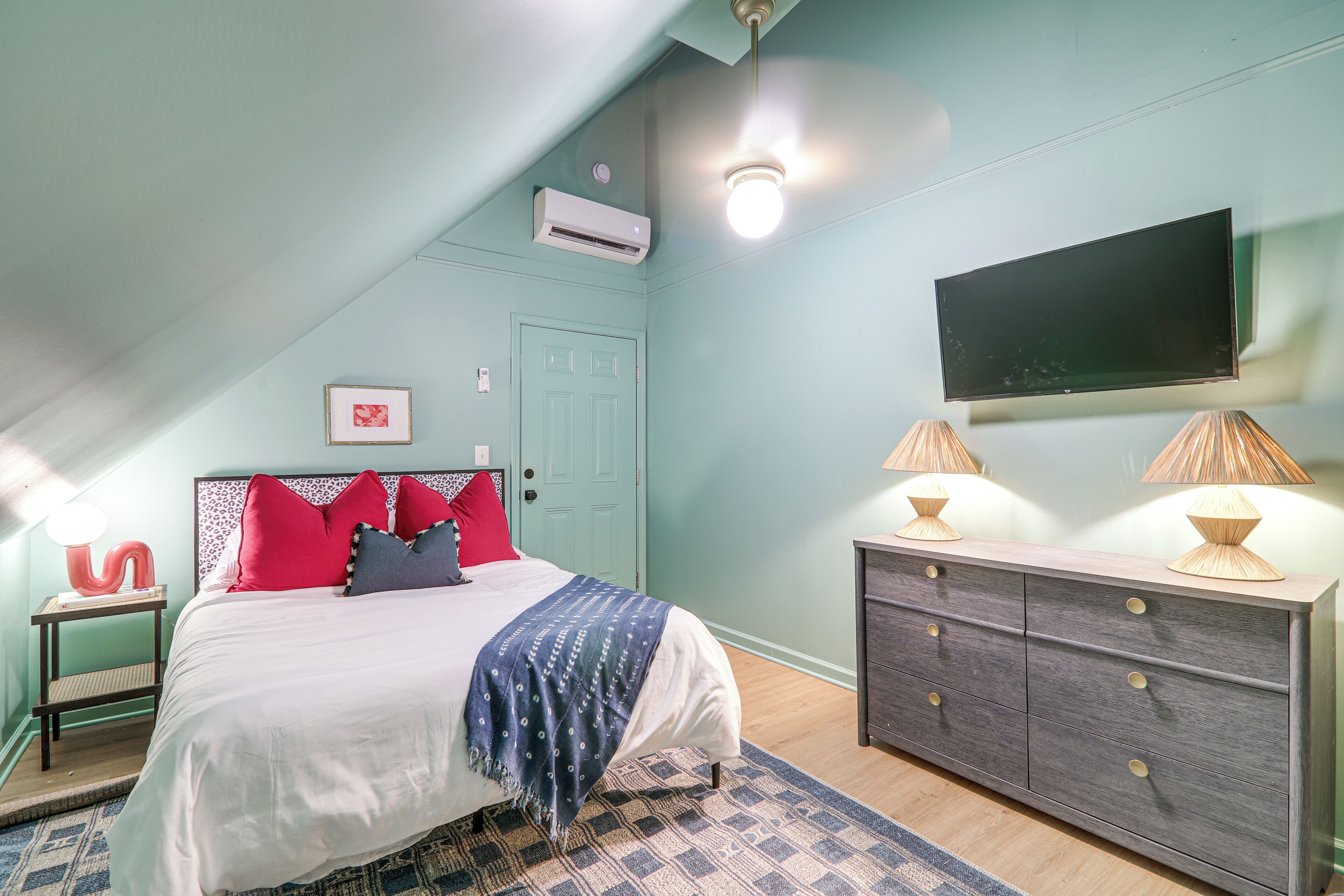 Une chambre à coucher comprenant un lit, une commode, un téléviseur et un appareil de climatisation.