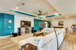 A modern living room with a sofa, TV, and a ceiling fan.