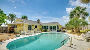Una propiedad residencial con piscina, terraza cubierta y patio cercado con palmeras.