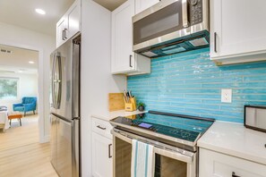 Eine moderne Küche mit Edelstahlgeräten, einer blauen Fliesenrückwand und einem Holzer Schneidebrett.