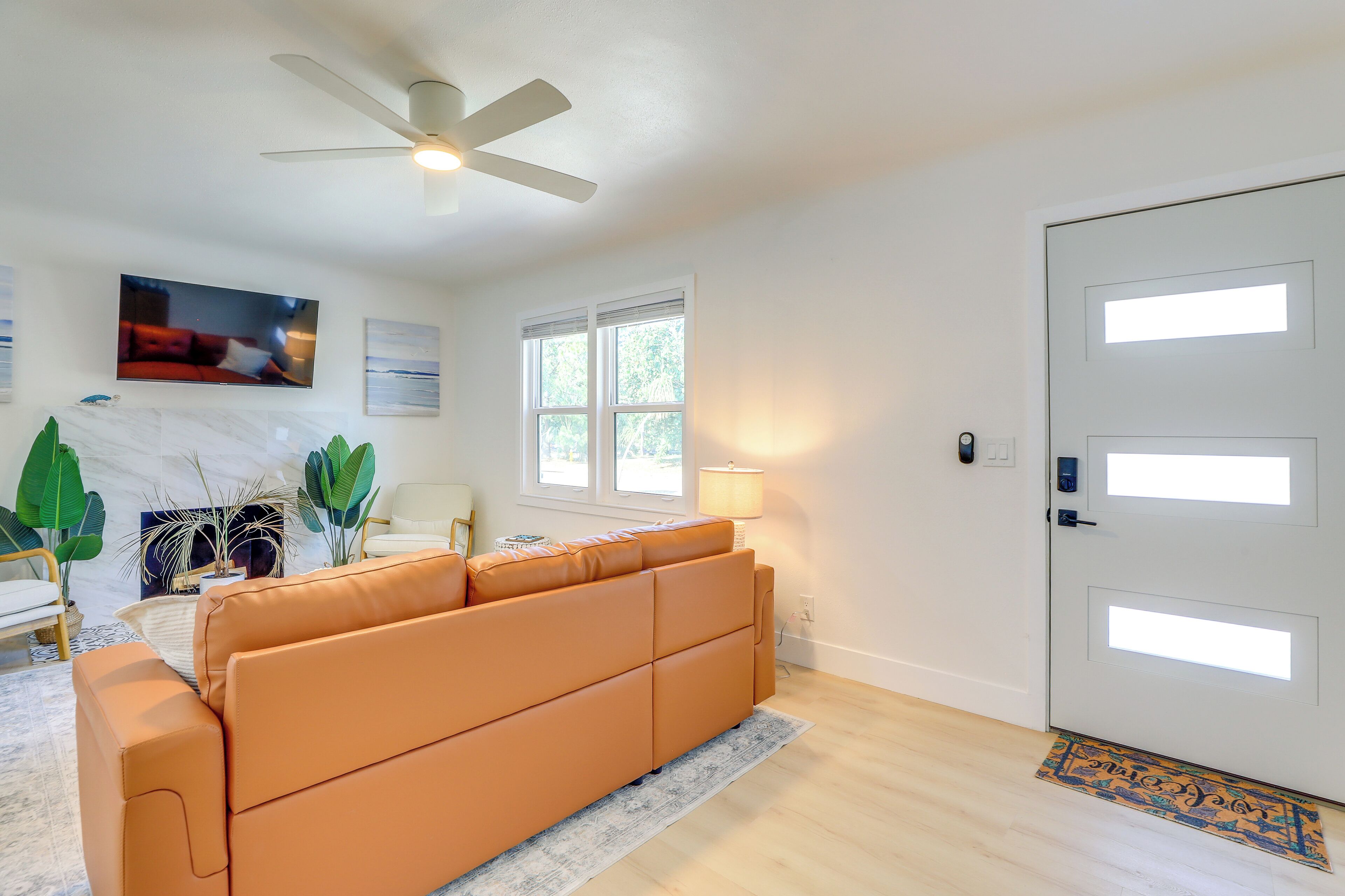 A modern living room with a sectional sofa, a ceiling fan, a TV, and a door with frosted glass panels.