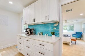 Eine moderne Küche mit weißen Schränken, einer blauen Spritzschutzwand und einer Kaffeemaschine.