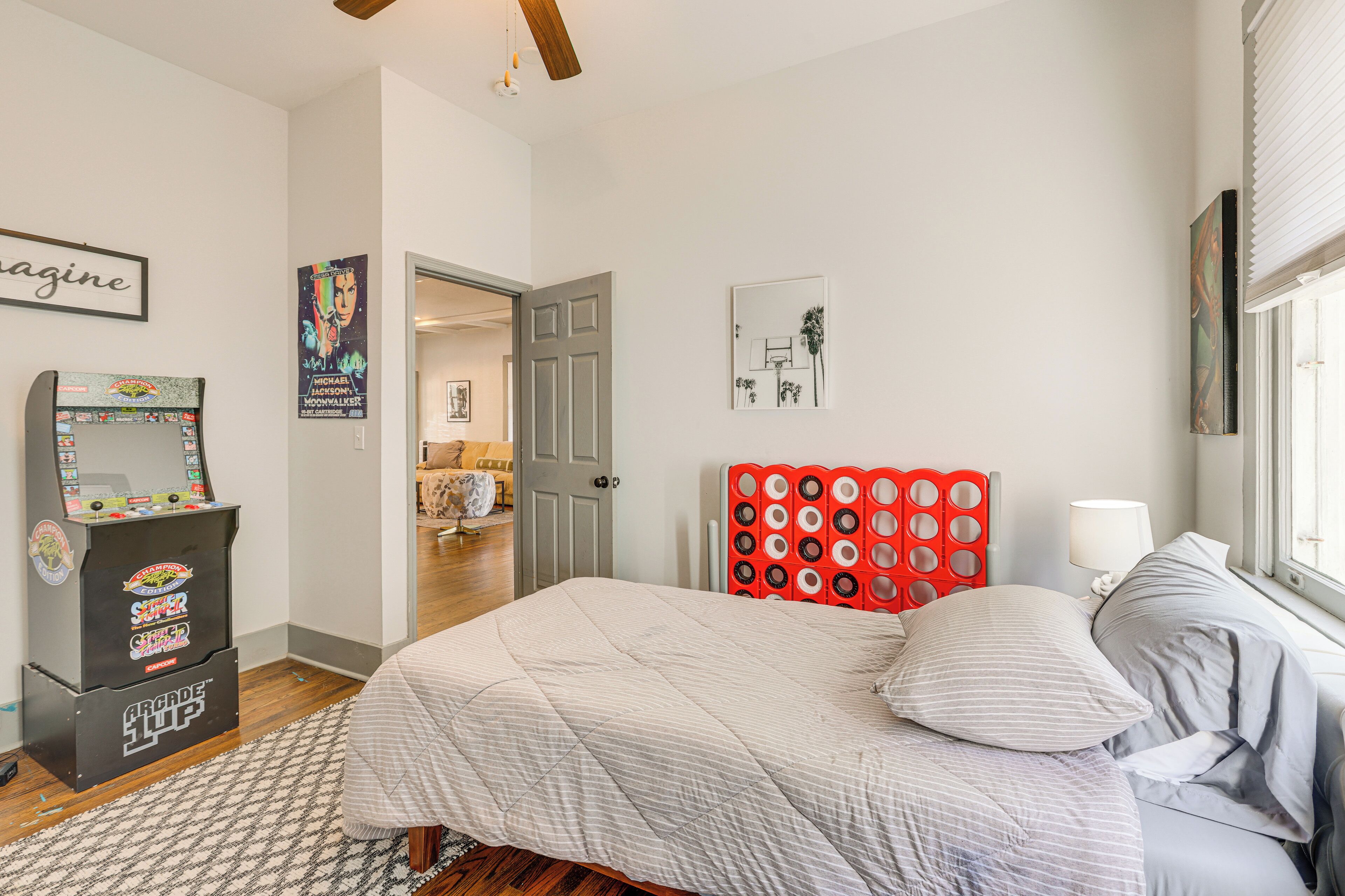 Une chambre à coucher avec un lit, une tête de lit rouge, une lampe et une affiche accrochée au mur.