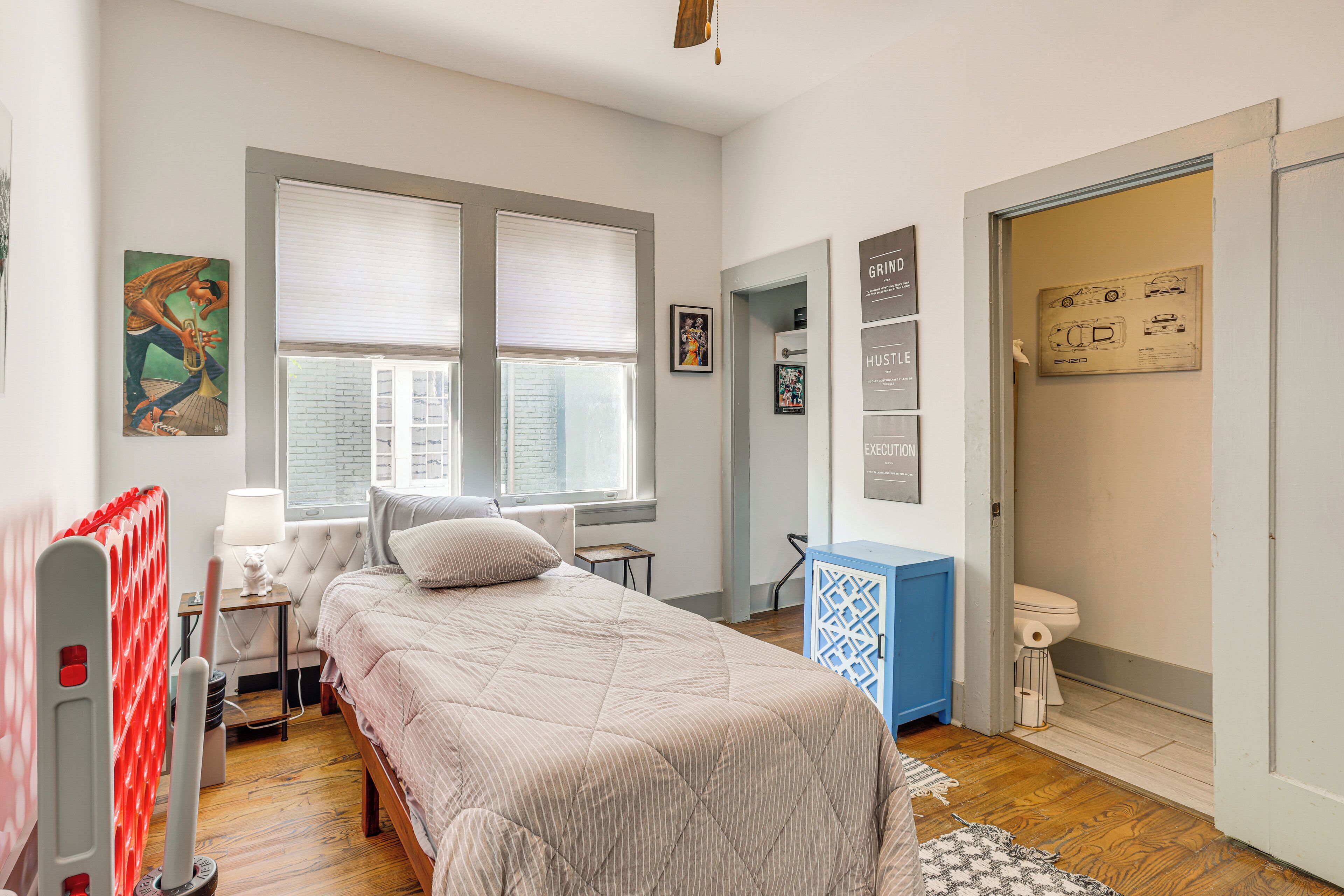 Un dormitorio con cama, radiador, escritorio y ventana con persianas.