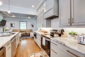Een moderne keuken met grijze kastjes, een marmeren werkblad en roestvrijstalen apparatuur.